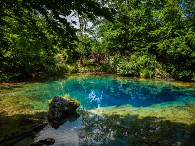 Helderblauw bergmeer omringd door groen bos langs de Route Zuidoost Europa.