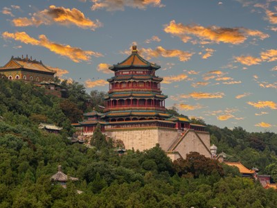 Zomerpaleis in Beijing met kleurrijke paviljoens op een beboste heuvel bij zonsondergang.