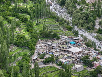 Groene terrassen en dorp in de Hunza-vallei, Pakistan, langs een rotsige rivierbedding.