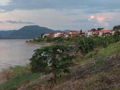 Rivieroever met dorp en bergen bij zonsondergang tijdens de rondreis Thailand Avontuur, 24 dagen.
