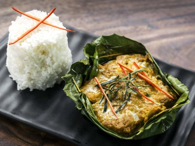 Thaise vis in bananenblad met kokos en kruiden, geserveerd met kleefrijst.
