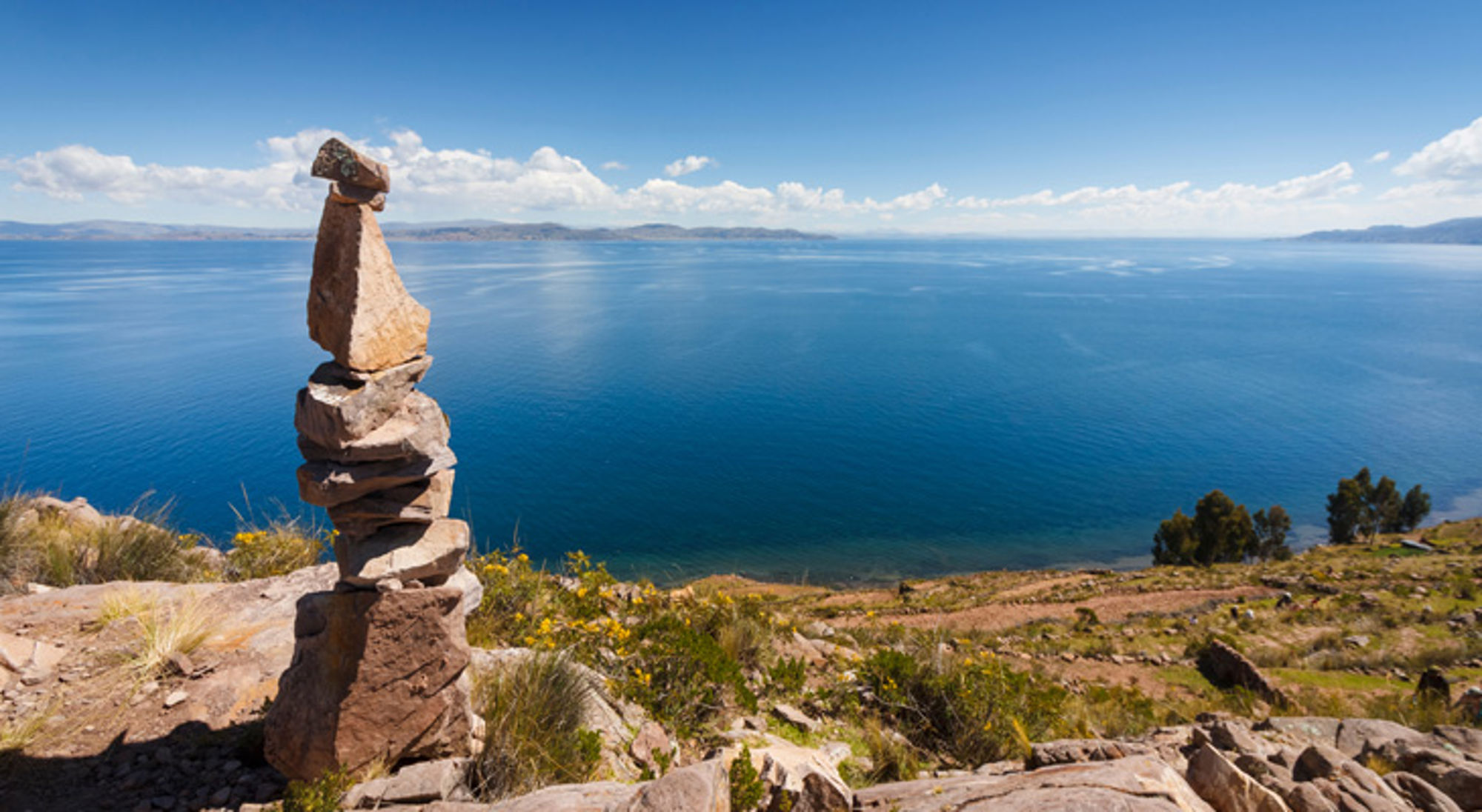 Puno Peru Stapel stenen aan de oever van het Titicacameer in Peru, met uitzicht over het blauwe water en bergen.