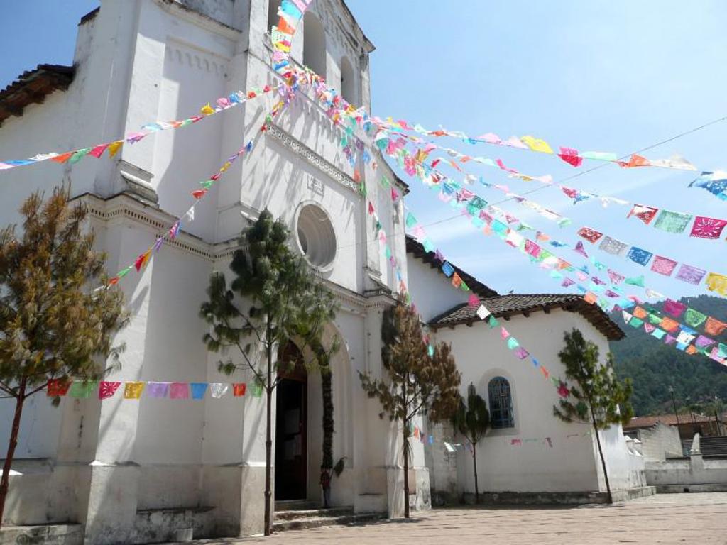 Witte kerk op dorpsplein met kleurrijke vlaggetjes, tijdens groepsrondreis Mexico, Guatemala en Honduras.