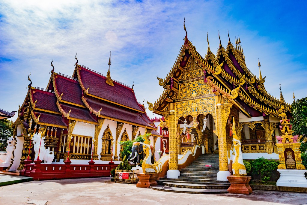 Gouden tempel met sierlijke daken en trappen bij een boeddhistisch complex in Thailand.