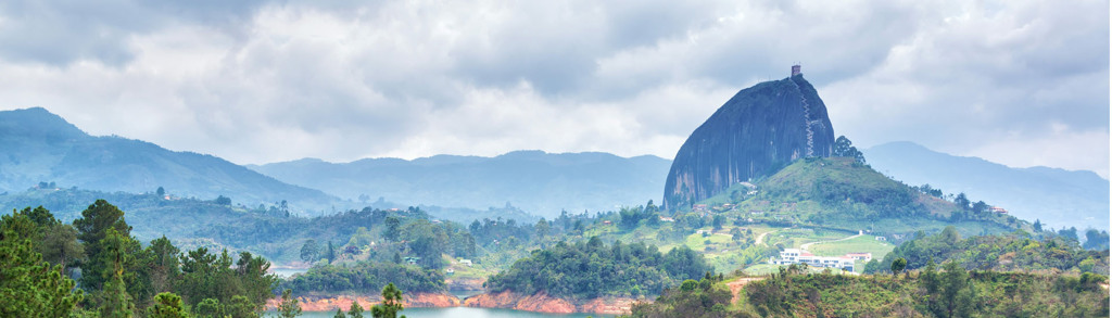 Panorama van El Peñón de Guatapé in Colombia, met groene heuvels en een meer.
