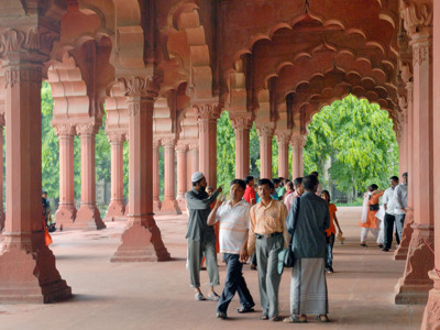 Bezoekers lopen door de zuilengalerij van een rood zandstenen paleis in India tijdens de Route India en Nepal.