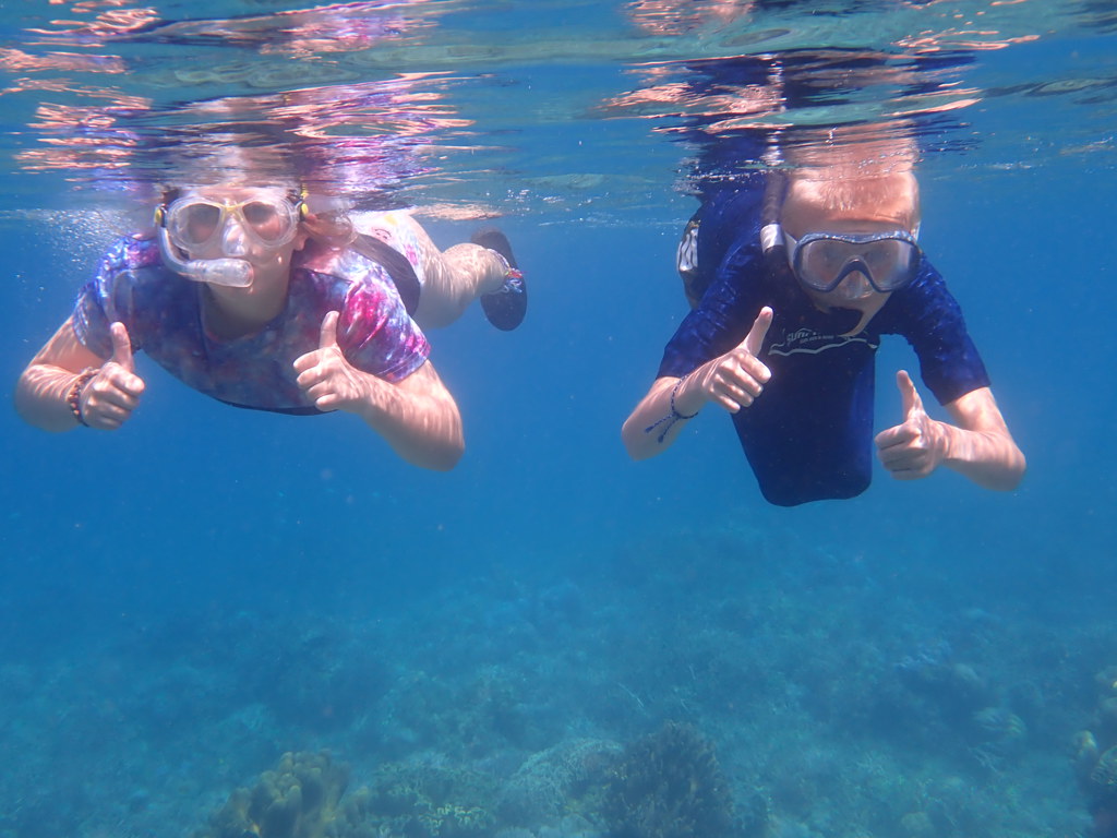 Twee kinderen snorkelen in helderblauw water bij de Kleine Sunda Eilanden, Indonesië.