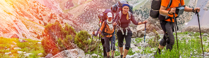 Wandelaars met rugzakken en wandelstokken op een bergpad in Nepal.
