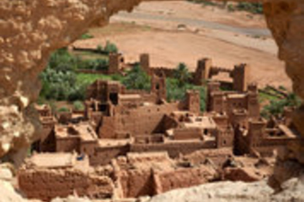 Oud kasbah-dorp met lemen gebouwen in een groene oase in Marokko.