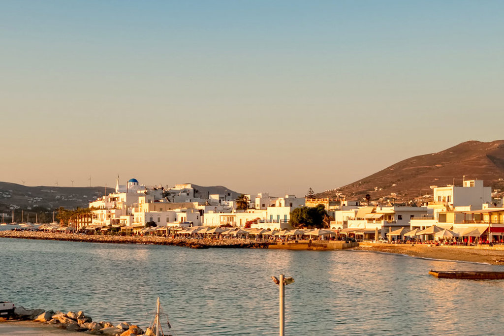 Boulevard en witte huizen aan zee op Naxos, Griekenland, bij zonsondergang.