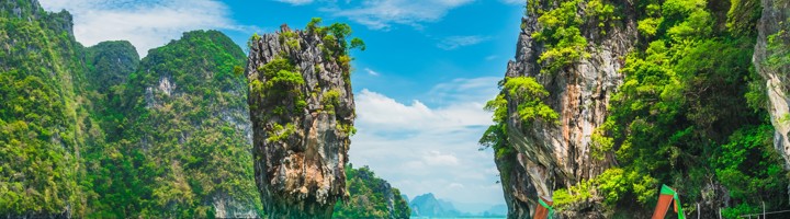 Longtailboten op het strand met kalksteenrotsen in Phang Nga Bay, Thailand.