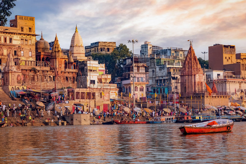 Drukke ghats aan de Ganges in Varanasi met tempels en boten bij zonsondergang tijdens een 22-35ers reis India.