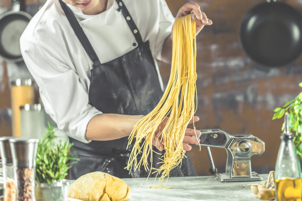 Kok maakt verse pasta met pastamachine tijdens familiereis in Zuid-Italië en Sicilië.