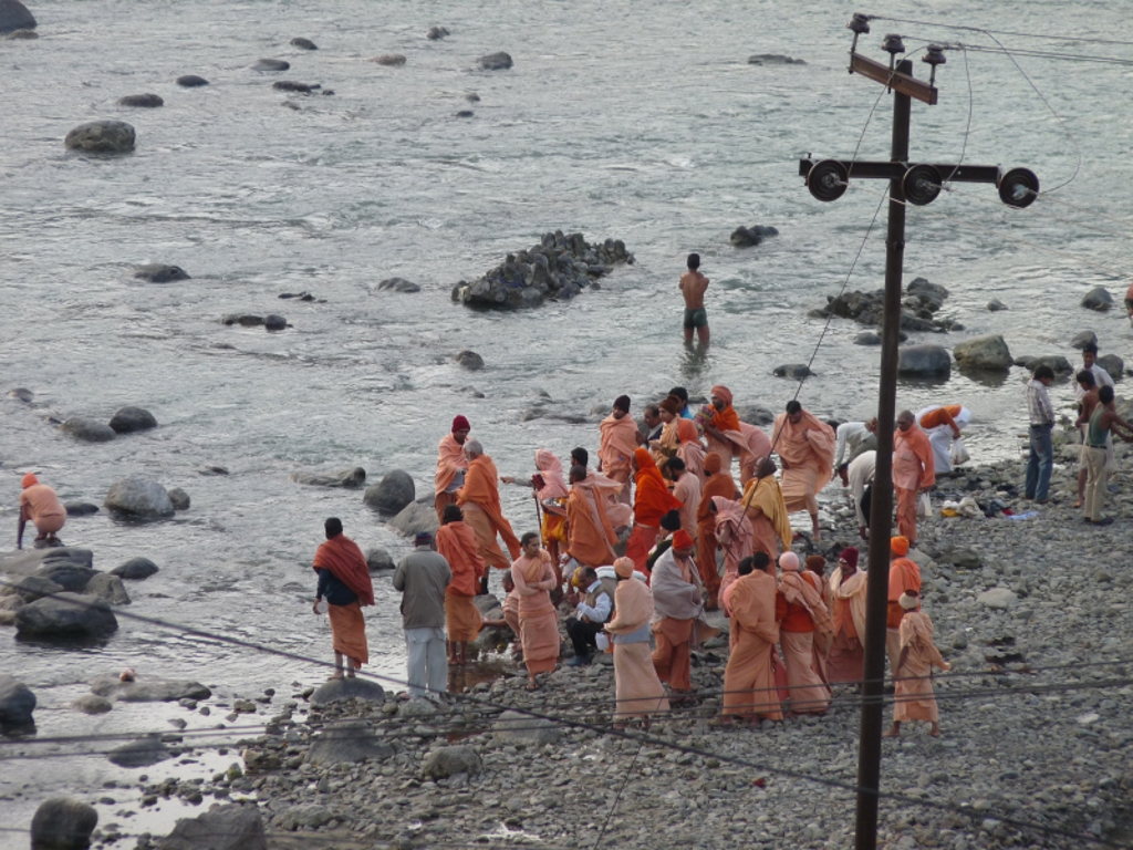 Pelgrims in oranje gewaden langs de rivier de Ganges in India.
