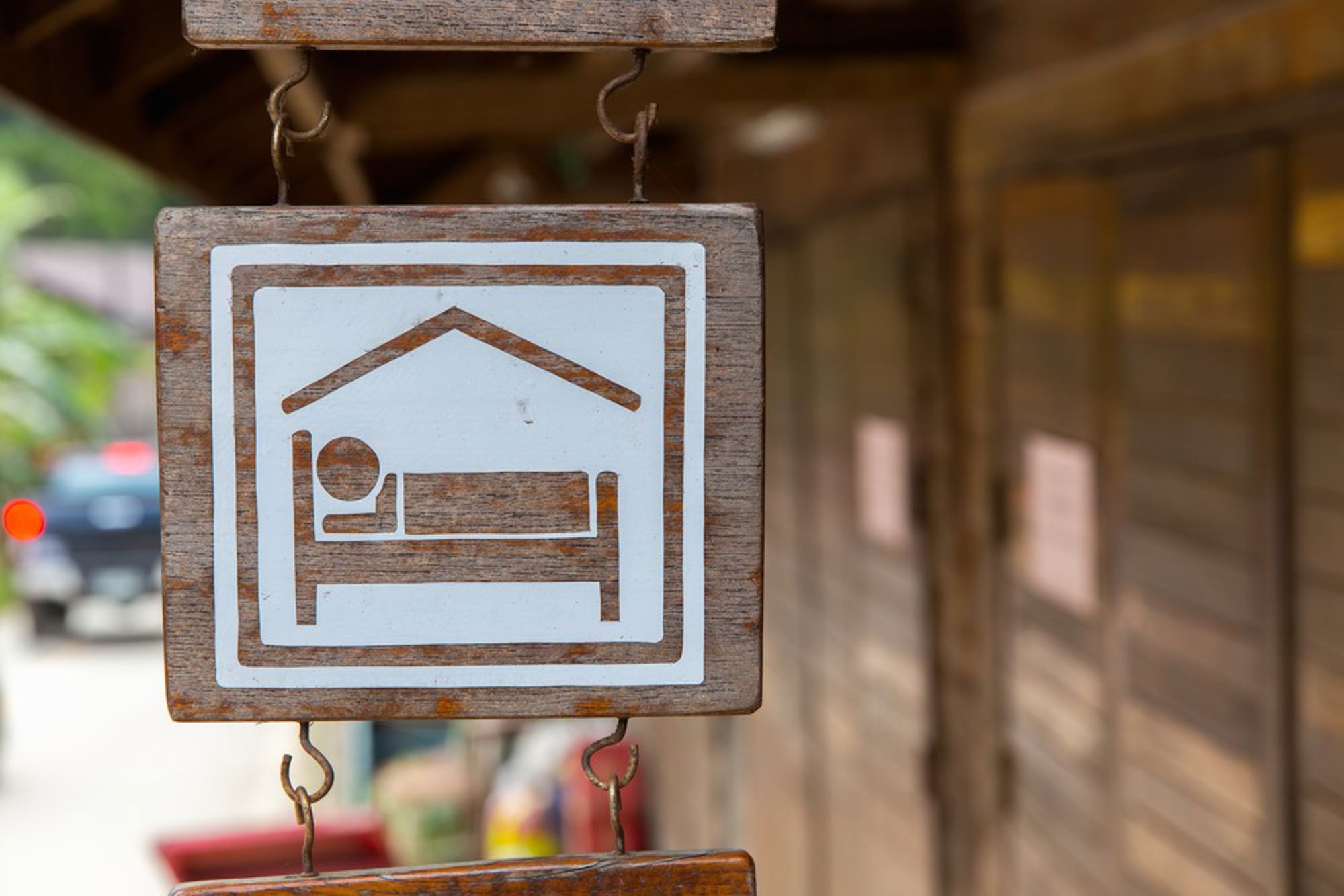 Houten bord met pictogram van een bed, als aanduiding voor een hotel of accommodatie.