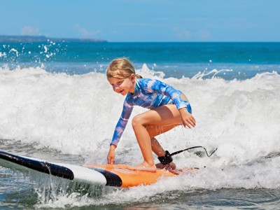 Kind surft op een surfboard in de golven aan het strand van Bali.