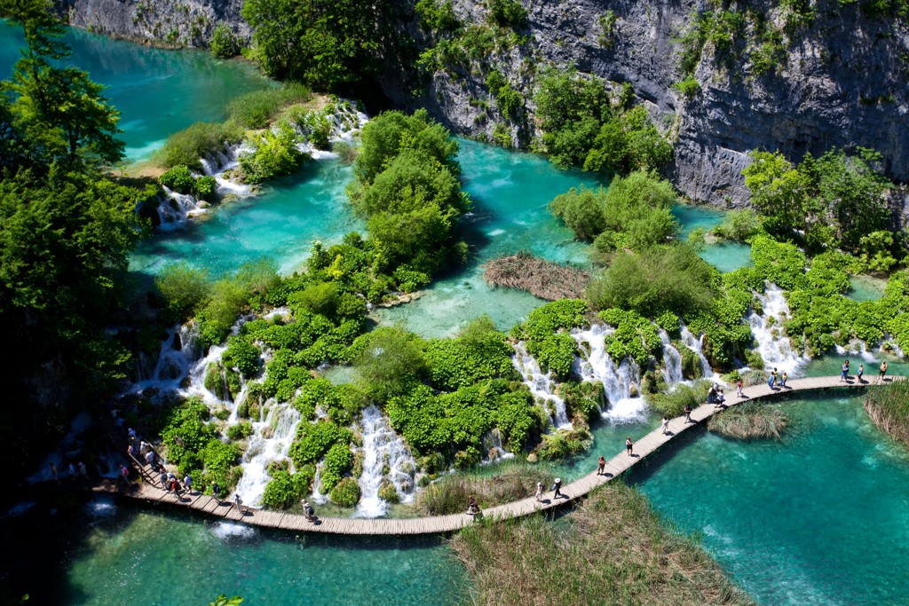 Houten wandelpad langs watervallen en turquoise meren in Nationaal Park Plitvicemeren, Kroatië.