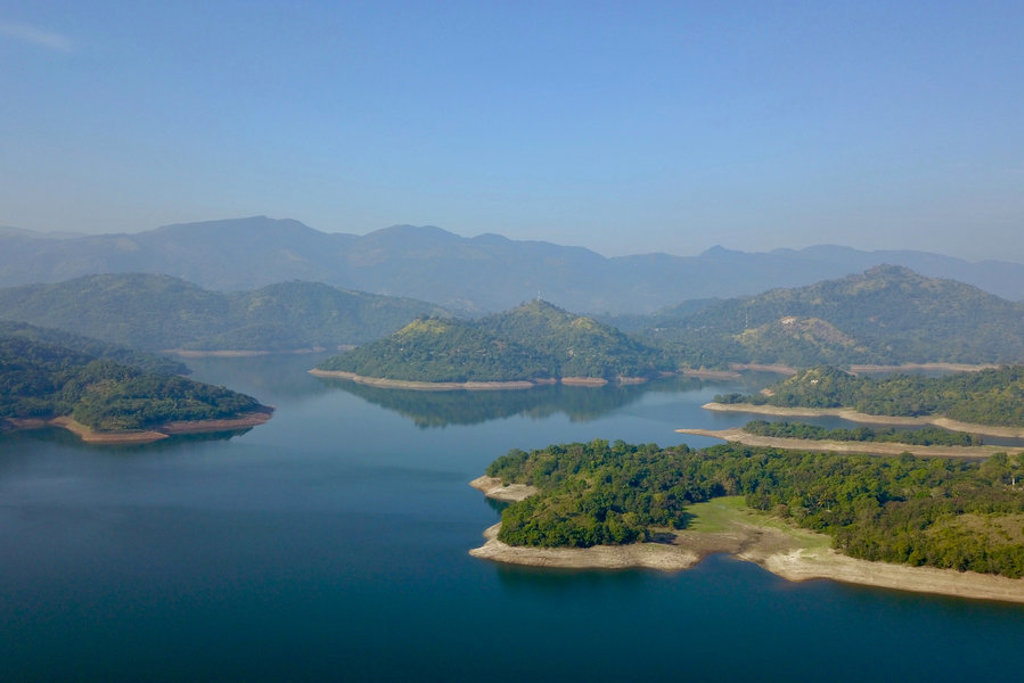 Uitzicht over een groot stuwmeer met groene eilandjes en bergen in Sri Lanka tijdens een familiereis.
