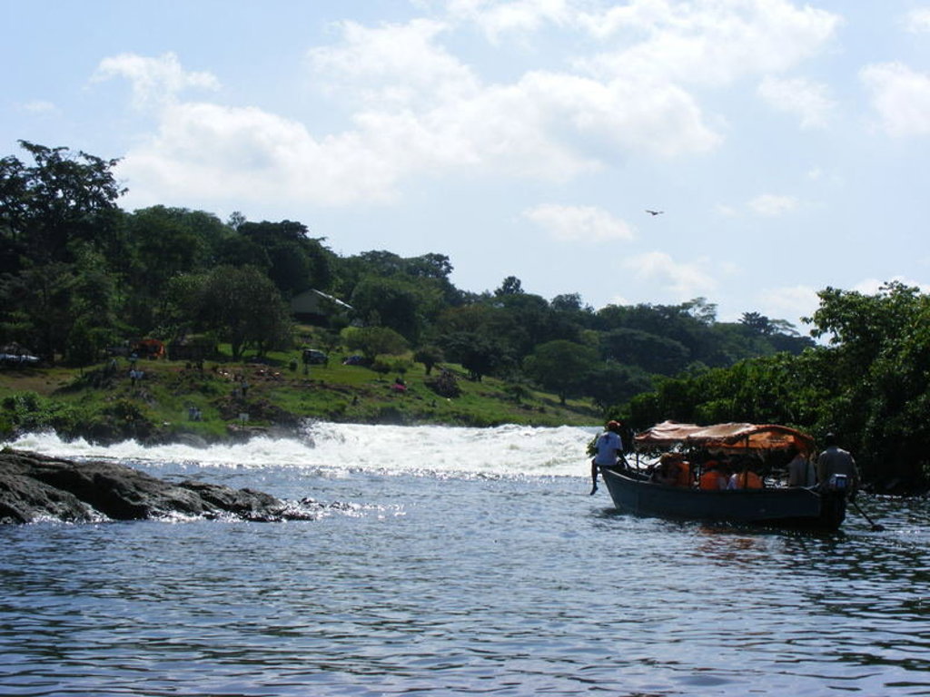 Boot vaart over de Nijl langs stroomversnellingen tijdens groepsrondreis Uganda en Rwanda.