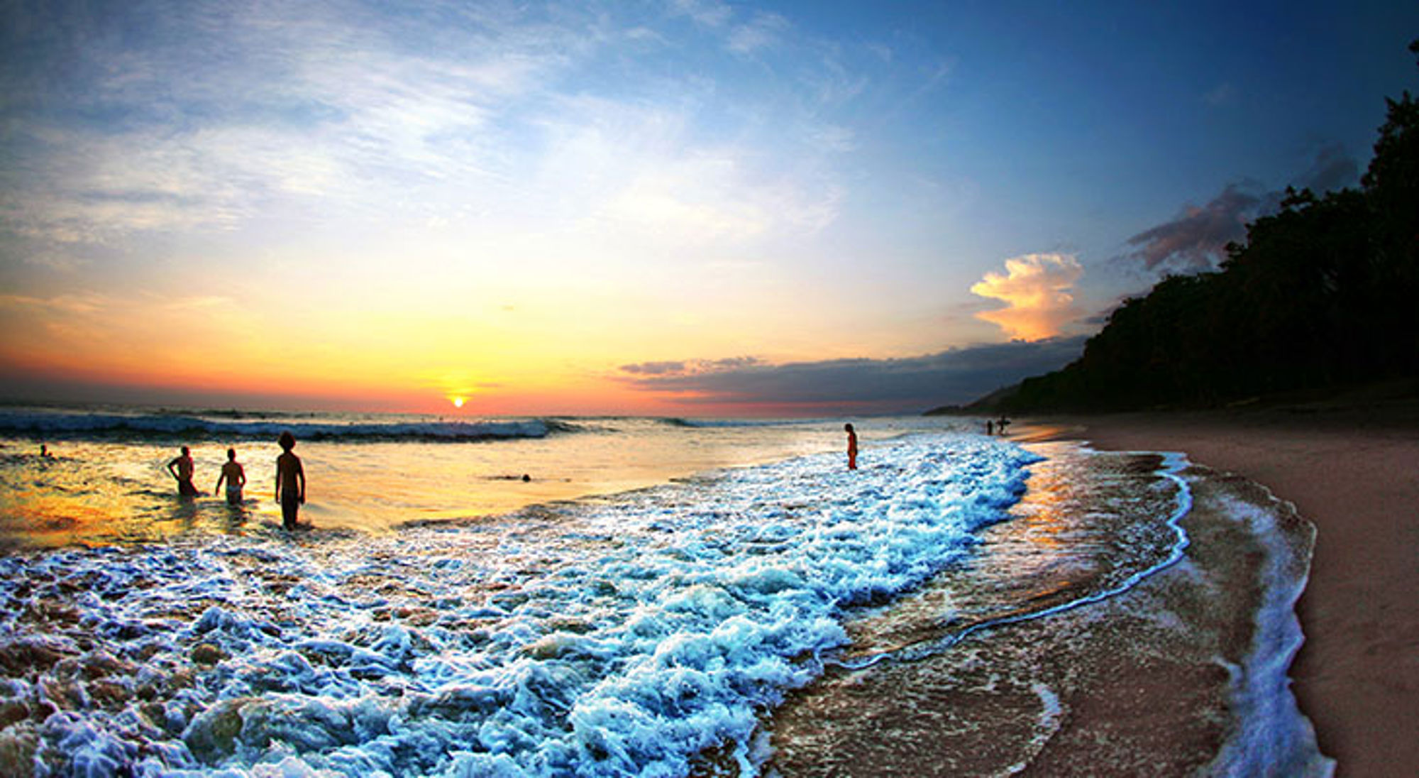 Zonsondergang in Montezuma Zonsondergang aan een strand in Costa Rica met golven en mensen in zee.