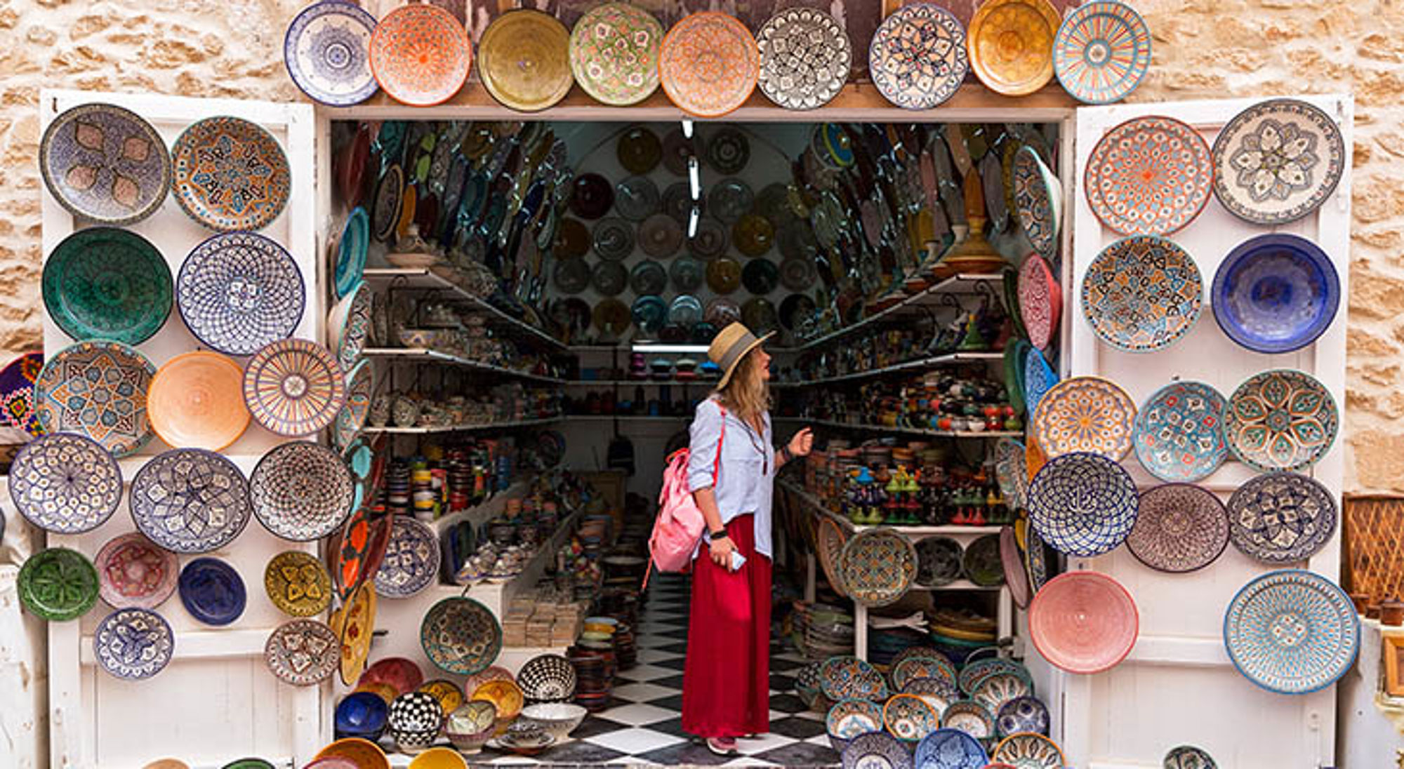 Essaouira Toerist in keramiekwinkel met kleurrijke Marokkaanse schalen en borden in een souk.
