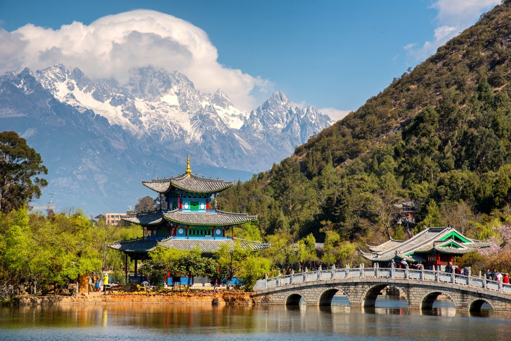 Traditionele Chinese pagode en stenen brug bij Lijiang, met besneeuwde bergen op de achtergrond tijdens groepsrondreis China.