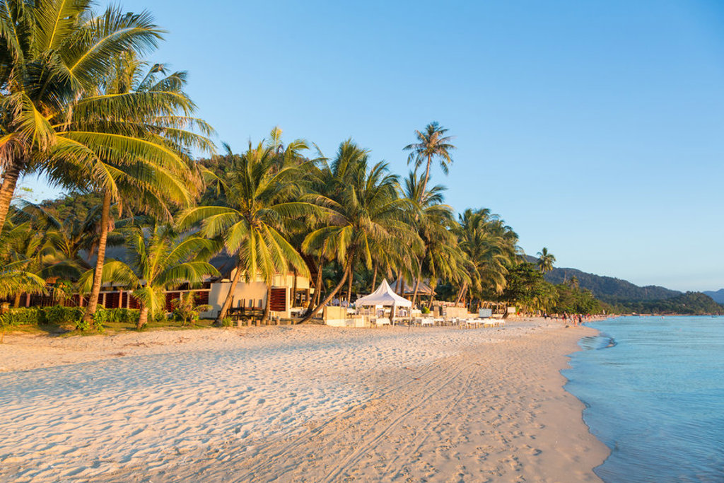 Palmenstrand met rustig zeewater bij zonsondergang tijdens familiereis Thailand, Laos en Cambodja.