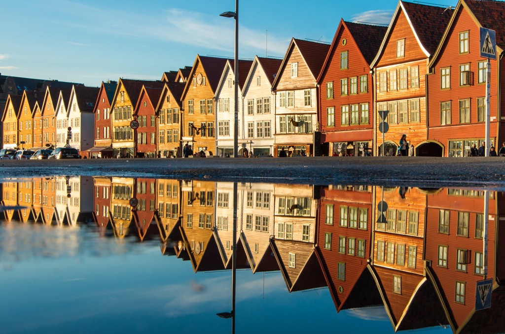 Gekleurde houten pakhuizen aan de kade in Bergen, met spiegeling in het water, tijdens een groepsrondreis Scandinavië.