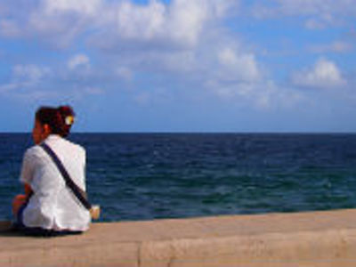Reiziger zit op de boulevard en kijkt uit over de zee in Cuba.