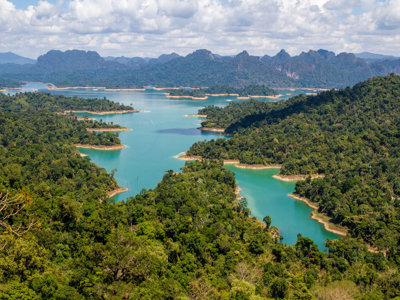 Uitzicht op turkoois stuwmeer met groene eilanden en bergen in Thailand tijdens de route mei t/m september.