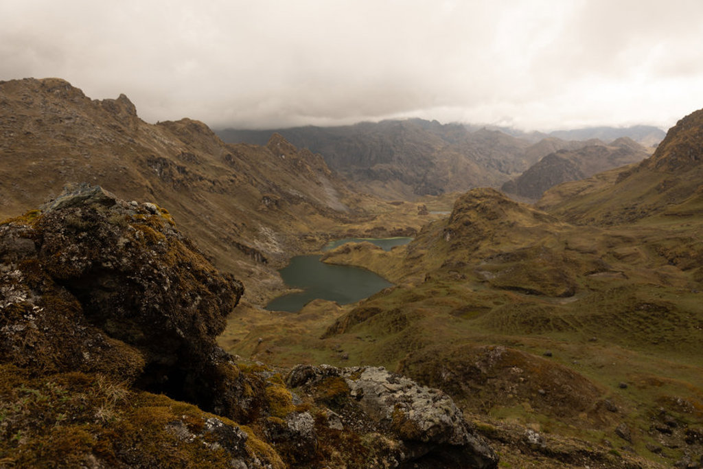 Berglandschap in Peru met een meer in een groene vallei onder een bewolkte lucht.