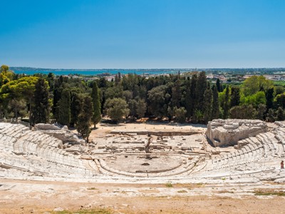 Grieks theater in Syracuse op Sicilië met uitzicht op zee en groene heuvels.