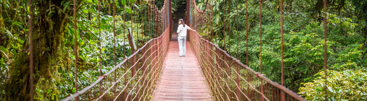 Reiziger loopt over hangbrug door het regenwoud in Costa Rica.