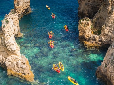 Kajakkers tussen rotskliffen in helderblauw water bij Lagos, Portugal.