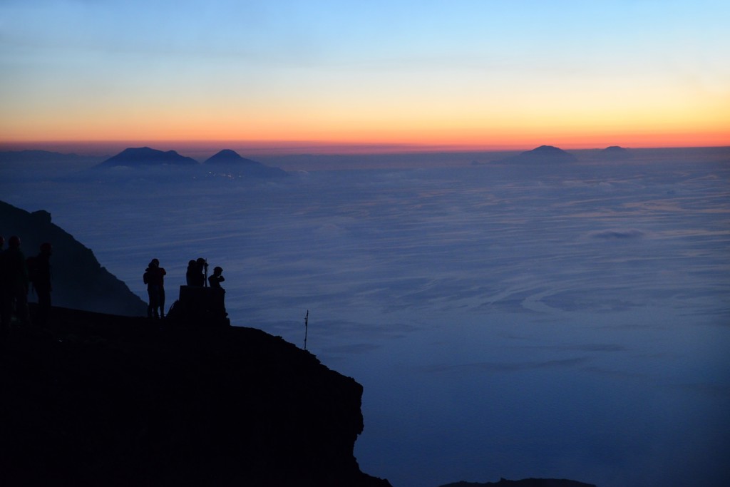 Wandelaars op een uitkijkpunt bij zonsondergang met uitzicht op de Eolische Eilanden, Sicilië.