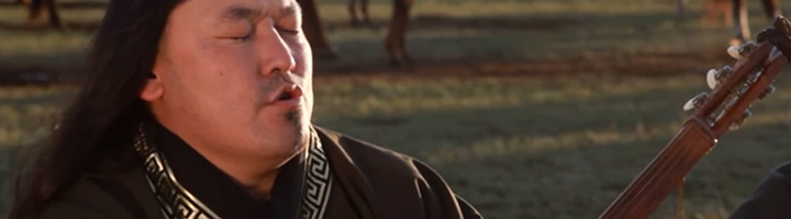 Muzikant in traditionele kleding speelt snaarinstrument in een Aziatisch landschap.