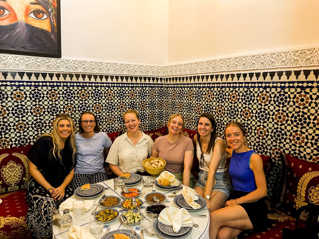 Vriendengroep geniet van Marokkaanse maaltijd in traditioneel restaurant tijdens 22-35ers groepsrondreis Marokko.