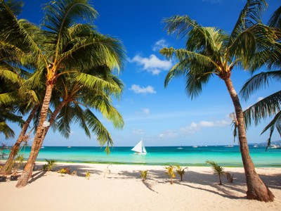Palmbomen op wit zandstrand met turquoise zee en zeilboot, Malediven tijdens de route Sri Lanka en Malediven.