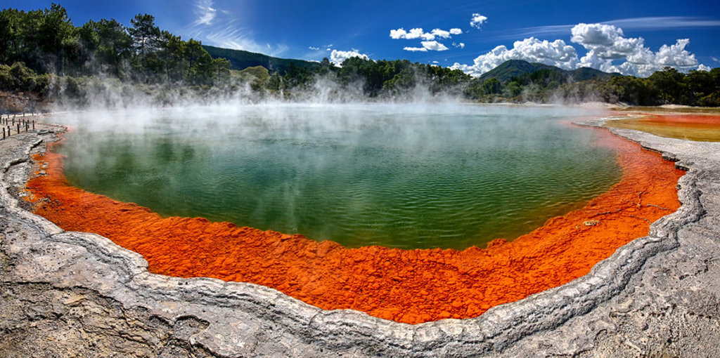 Stomende warmwaterbron met groen water en oranje mineraalrand in Rotorua, Nieuw-Zeeland.