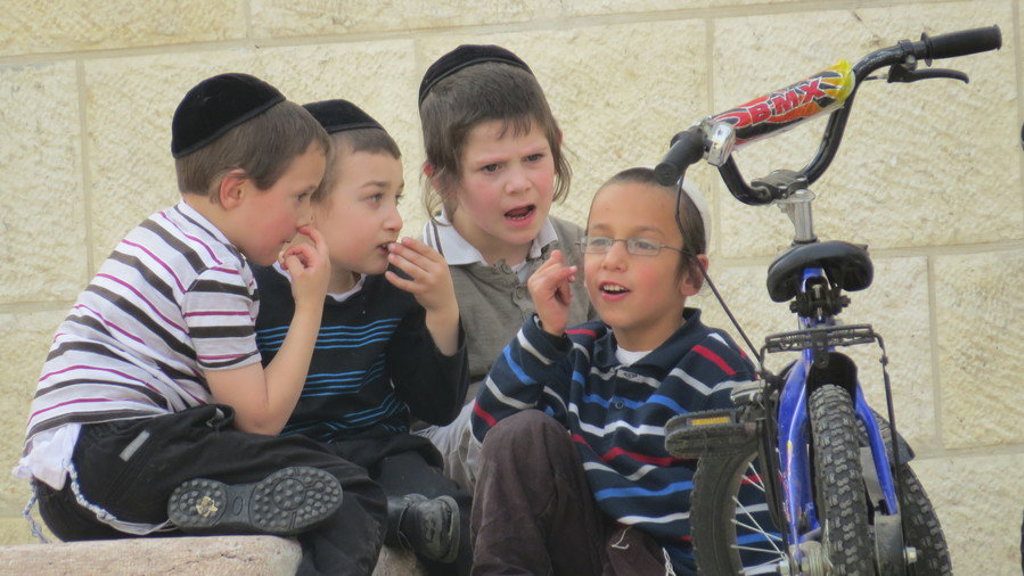 Joodse jongens praten samen op straat naast een blauwe kinderfiets in Israël.