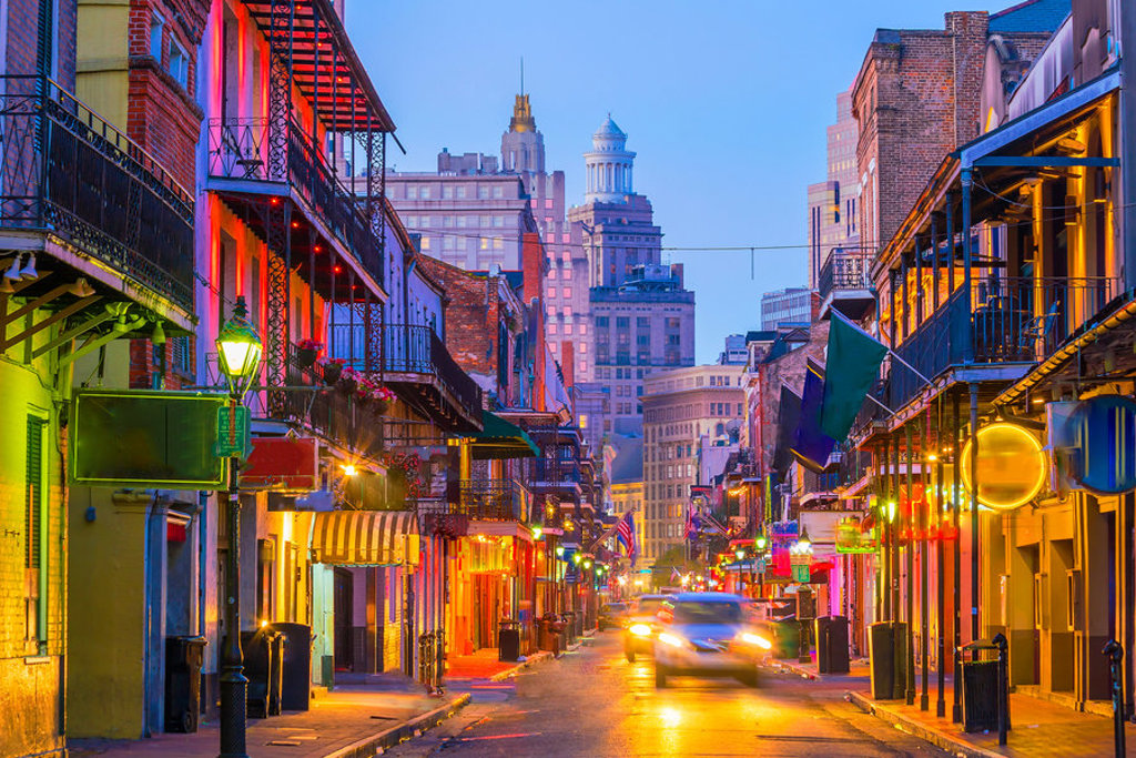 Verlichte straat in de French Quarter in New Orleans bij schemering, met balkons en historische gebouwen.