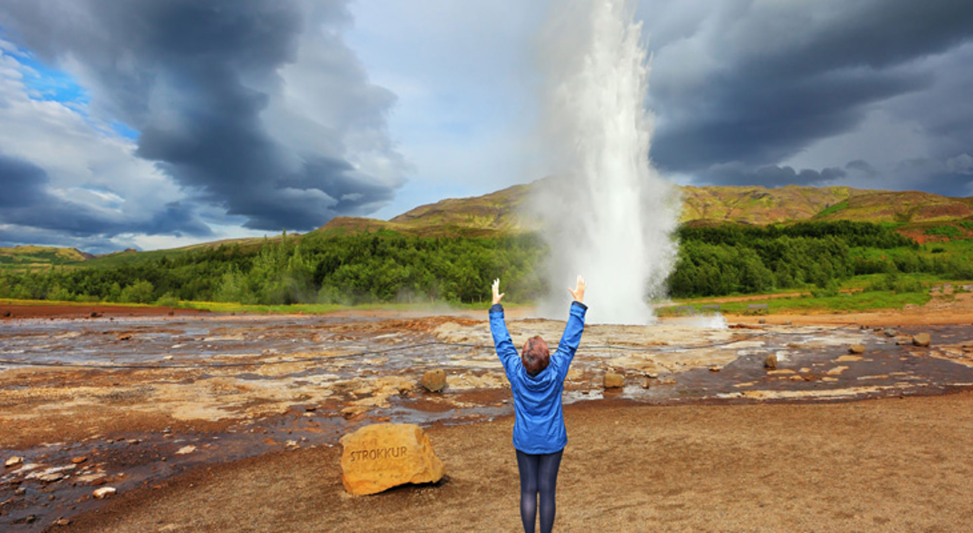 Strokkur geiser IJsland Bezoeker kijkt naar de uitbarstende Strokkur-geiser in IJsland.