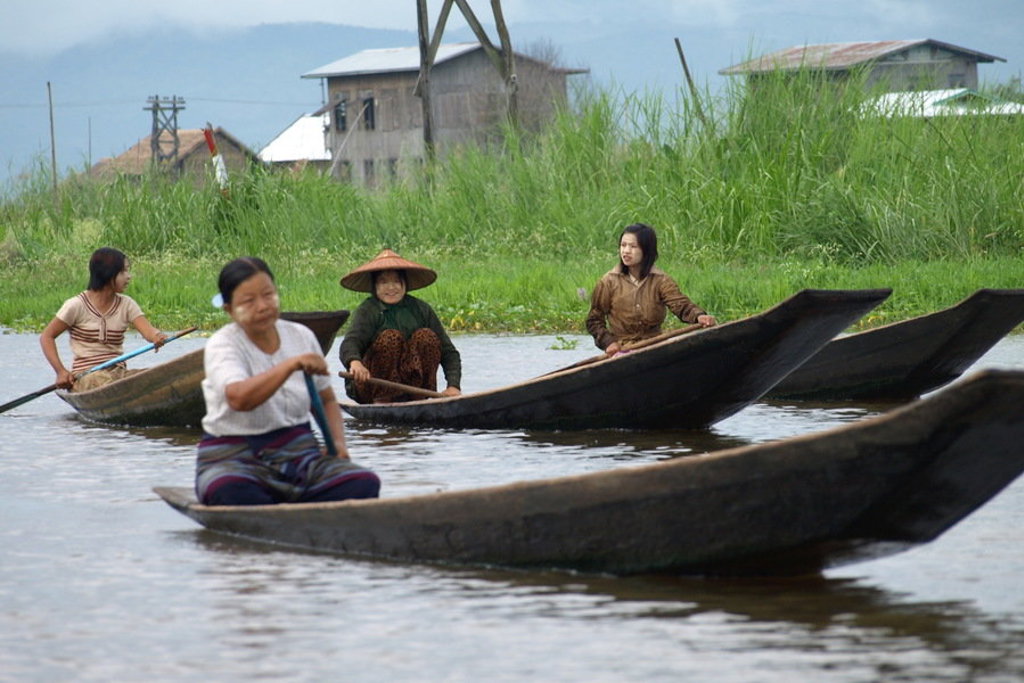 Vrouwen peddelen in houten kano’s op het Inlemeer in Myanmar, tijdens een groepsrondreis langs hoogtepunten.
