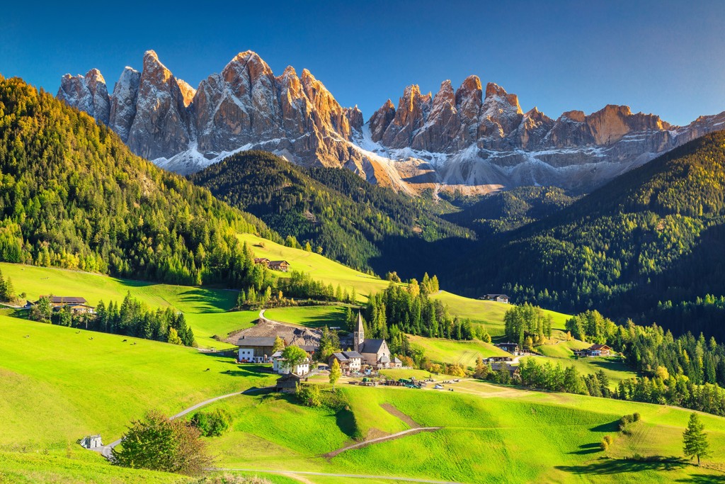 Alpenlandschap in Centraal Europa met bergtoppen, groene valleien en dorpje met kerk.