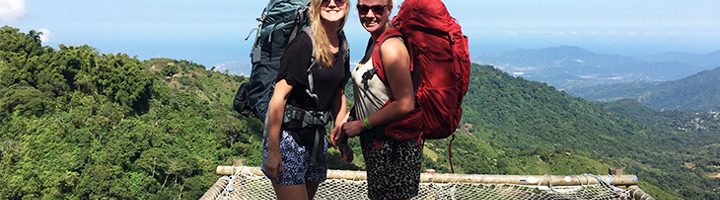 Twee jongvolwassen backpackers op uitzichtpunt met bergen op de achtergrond tijdens een singlereis.