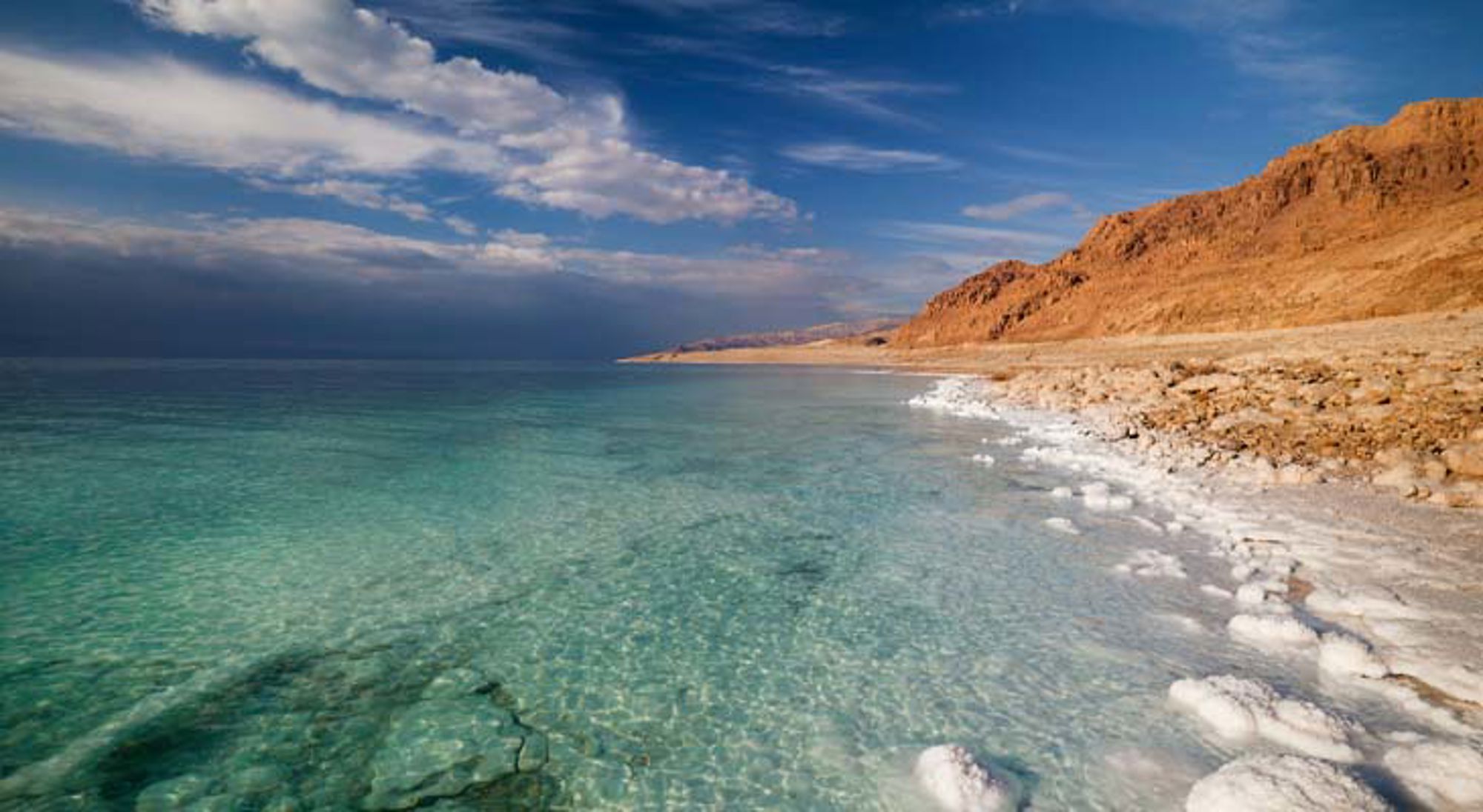 Dode Zee Jordanië Woestijnlandschap in Jordanië met rotsformaties en zandduinen bij zonsondergang.