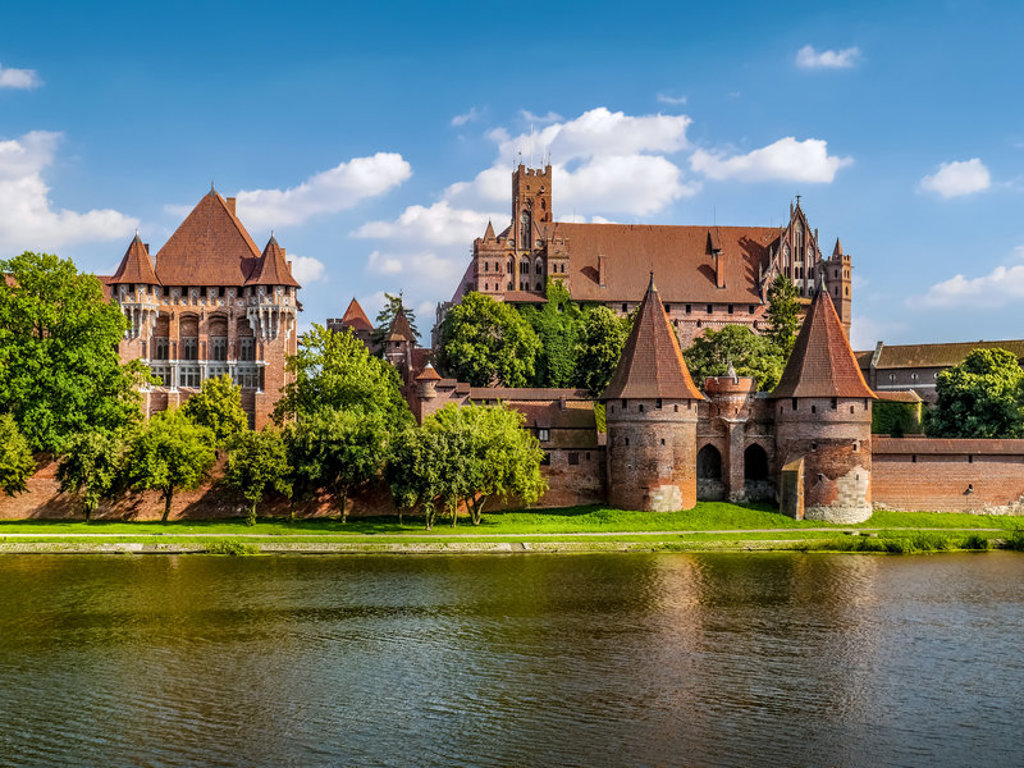 Kasteel Malbork aan de rivier de Nogat in Polen, met middeleeuwse torens en stadsmuren.