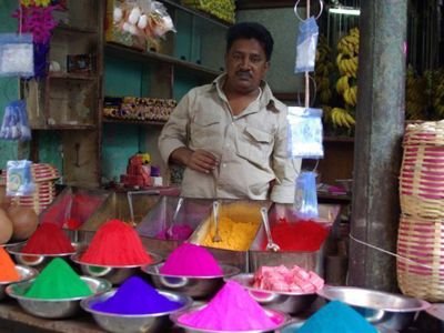 Marktkraam in Zuid-India met verkoper en schalen vol felgekleurde kruidenpoeders.