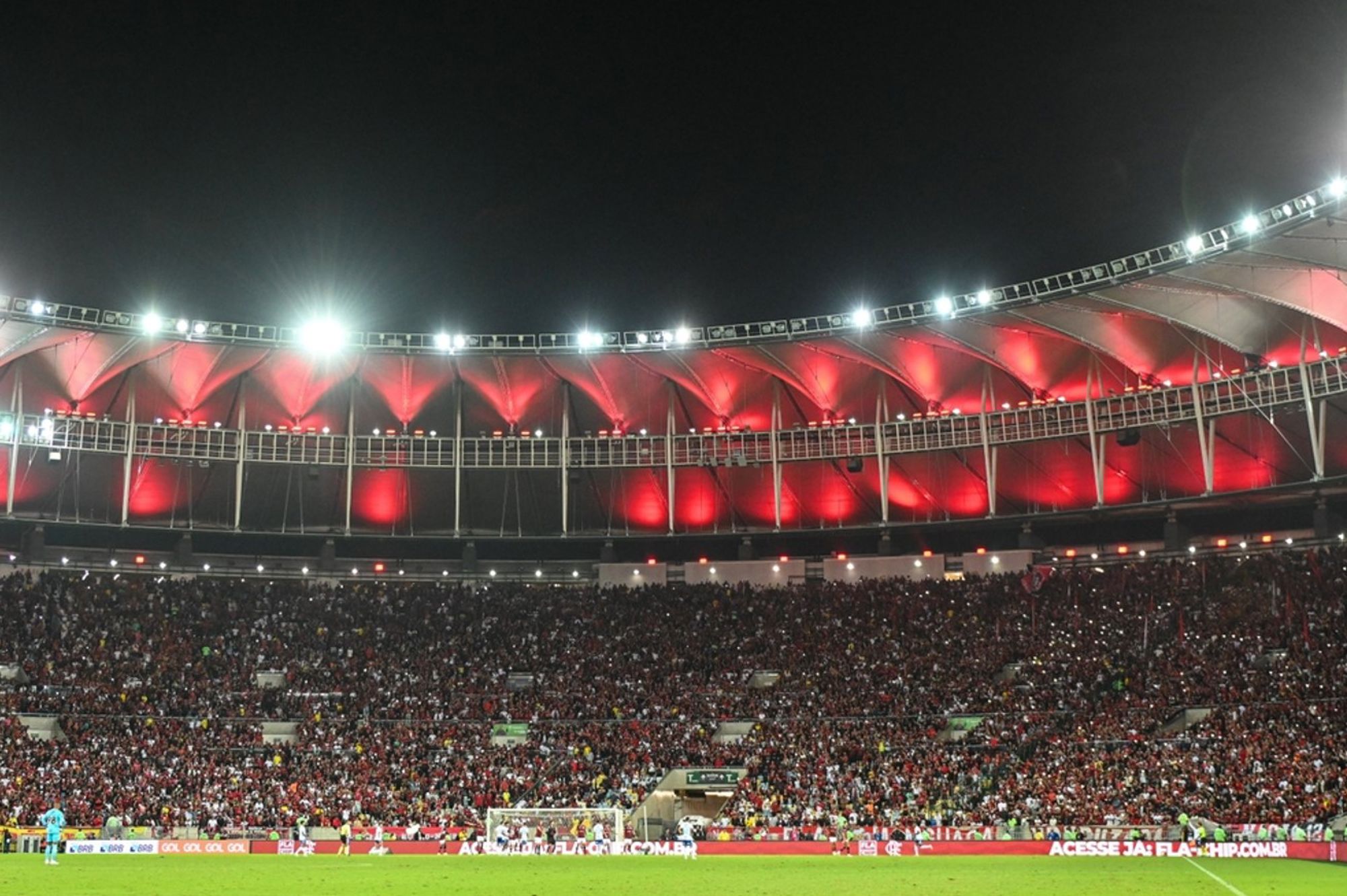 Verlicht voetbalstadion in Brazilië met volle tribunes tijdens een avondwedstrijd.