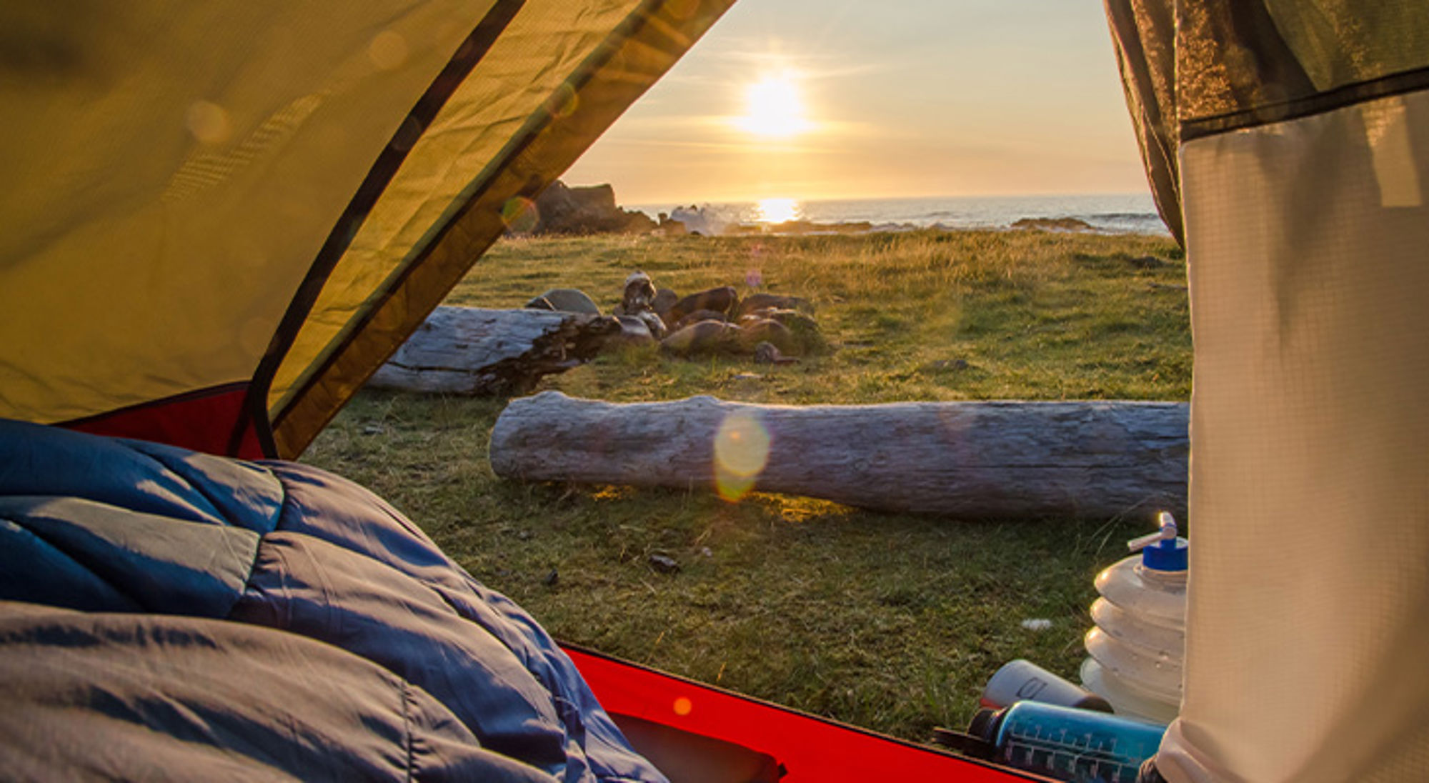 IJsland Uitzicht vanuit een tent op een kampeerplek aan zee bij zonsondergang.